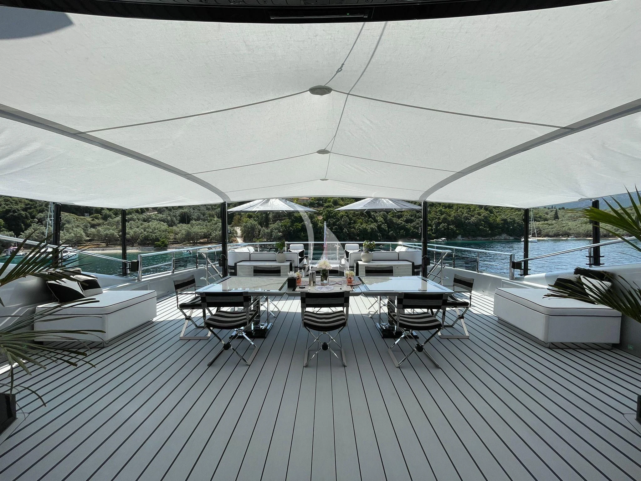 a deck with a large pool and a deck with chairs and umbrellas aboard OKTO Yacht for Charter