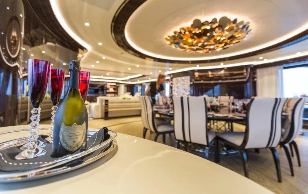 a table with a plate of food and a bottle of wine aboard OKTO Yacht for Charter
