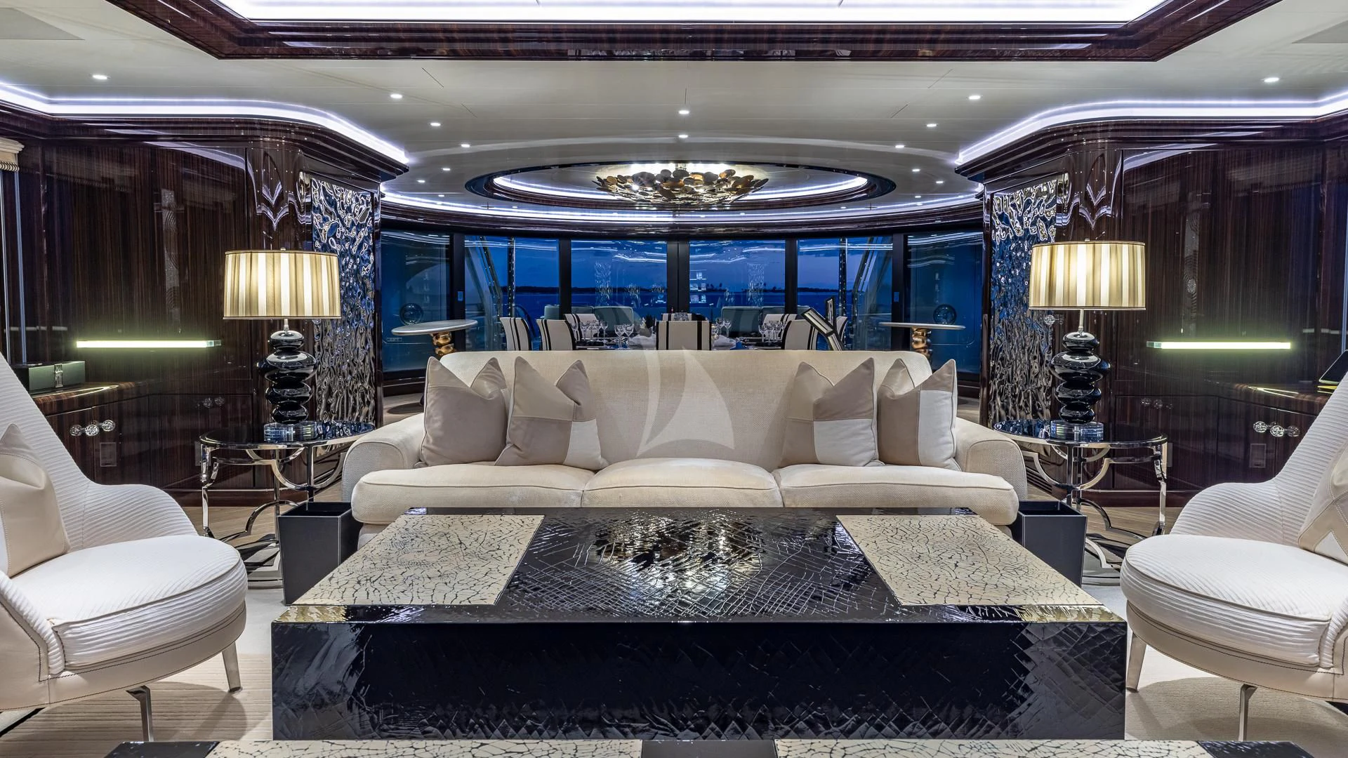 a large living room with a large white couch and a large chandelier aboard OKTO Yacht for Charter