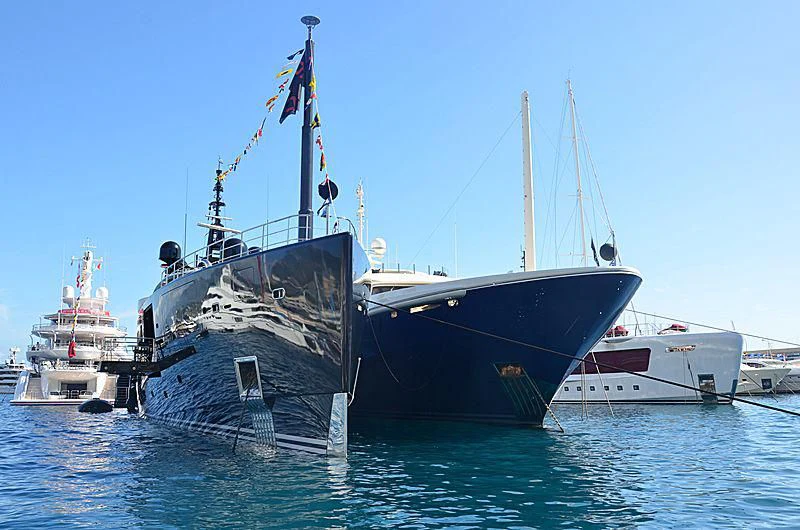 a large ship and a smaller boat in the water aboard OKTO Yacht for Charter