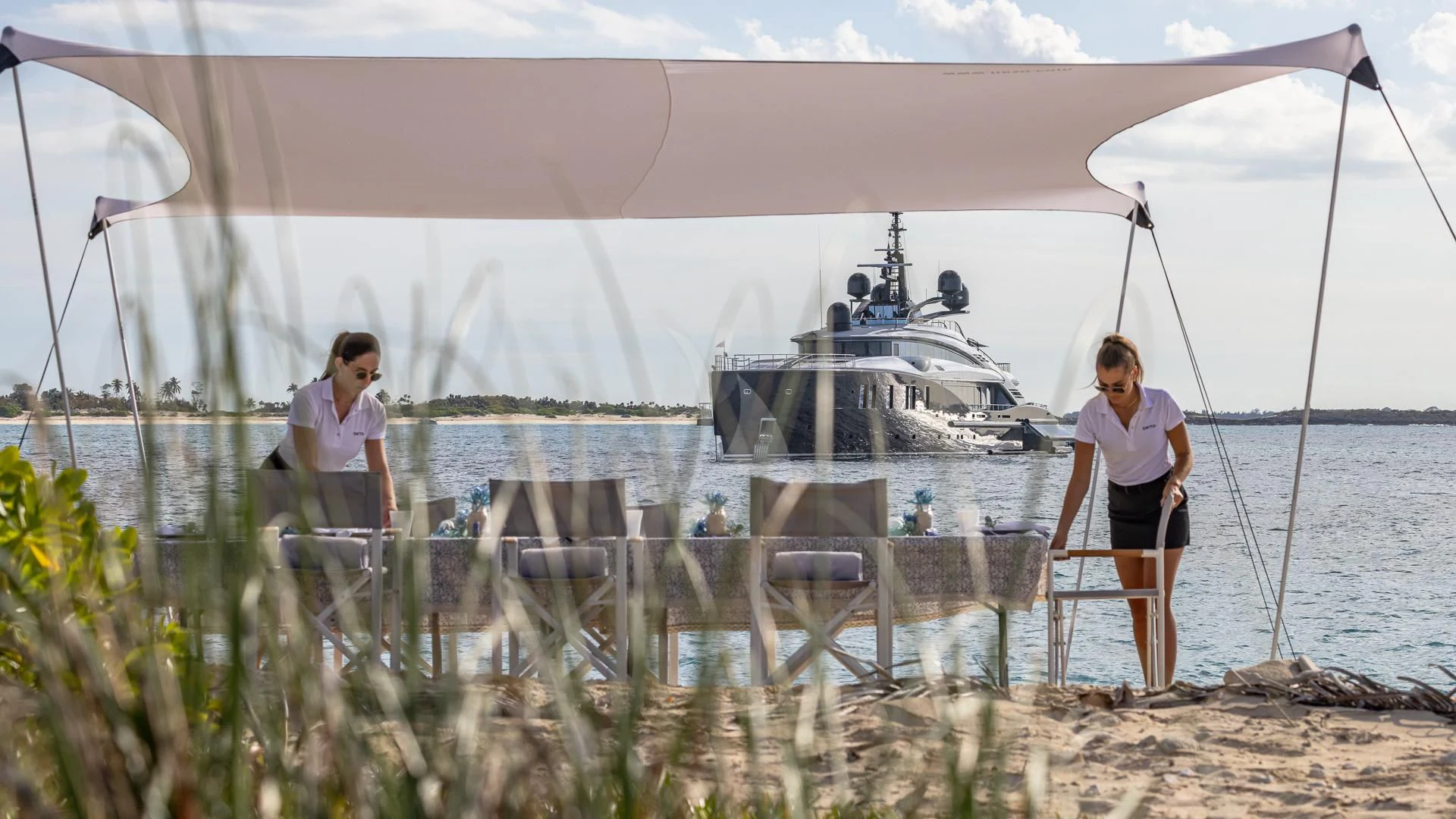 two women standing on a beach aboard OKTO Yacht for Charter
