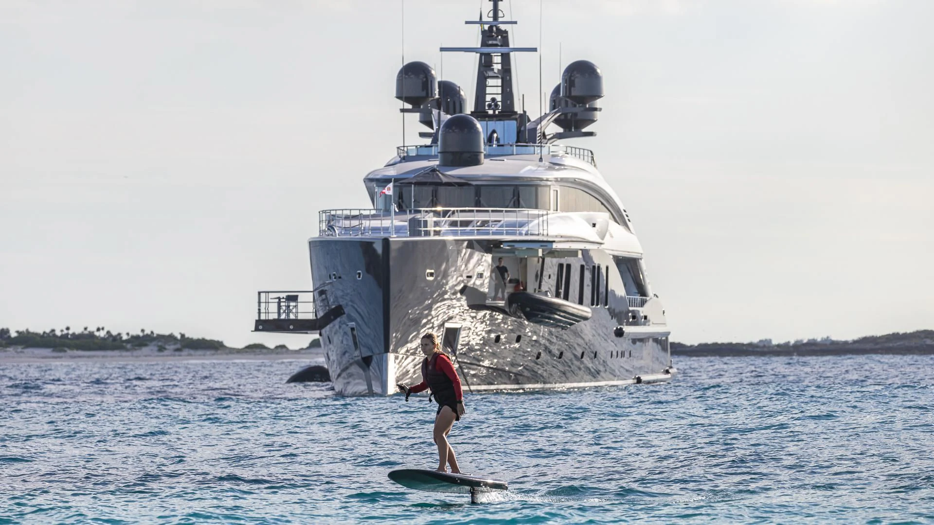 a person on a surfboard in front of a large ship aboard OKTO Yacht for Charter