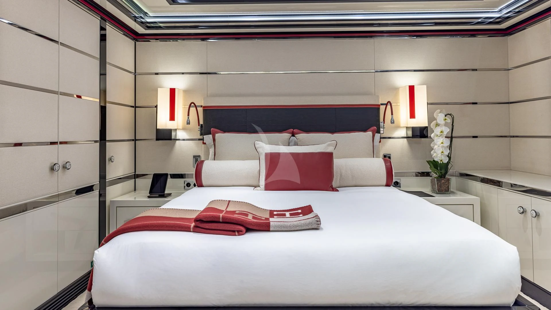 a bed with white sheets and red pillows aboard OKTO Yacht for Charter