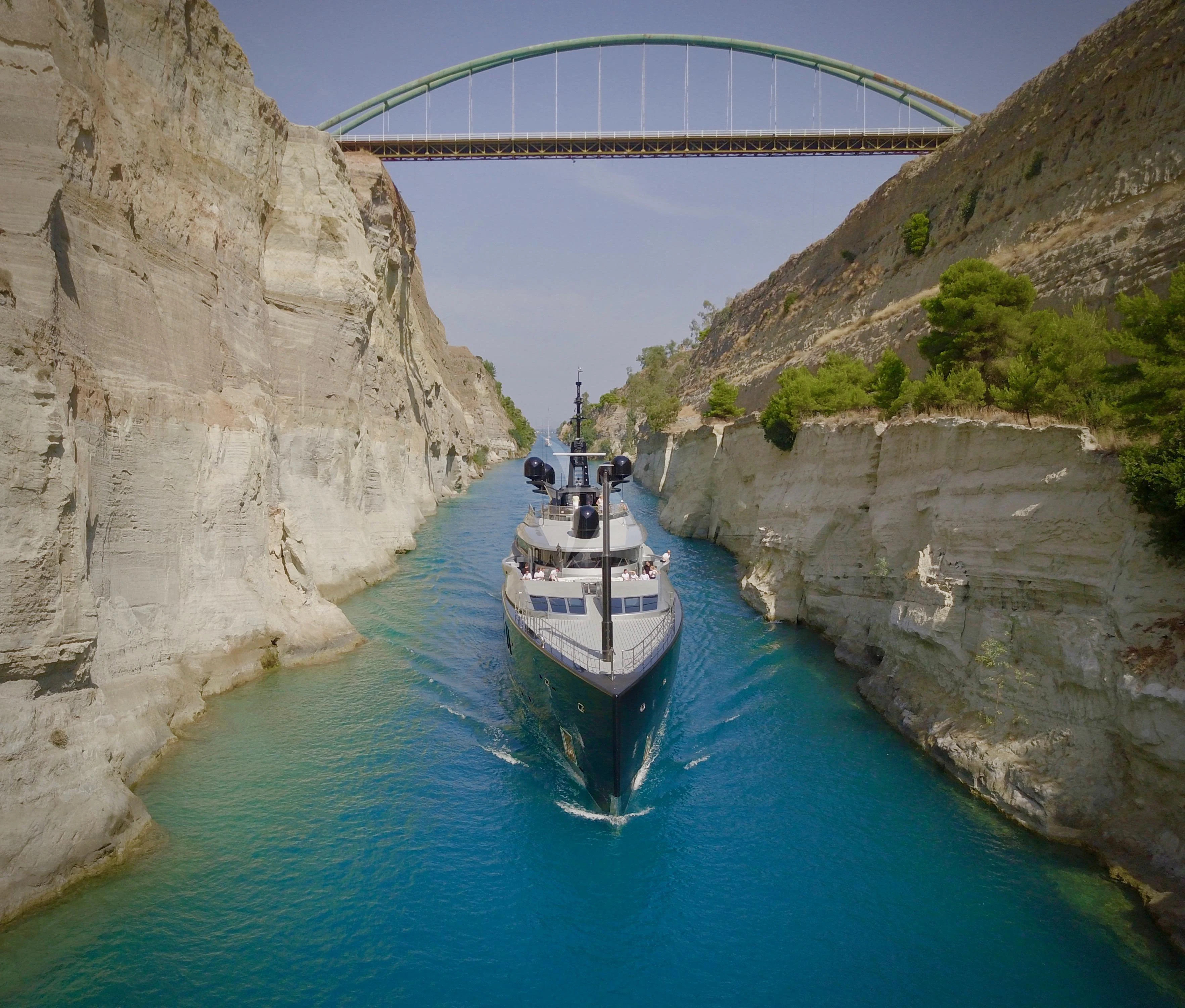 a boat in the water with Corinth Canal in the background aboard OKTO Yacht for Charter