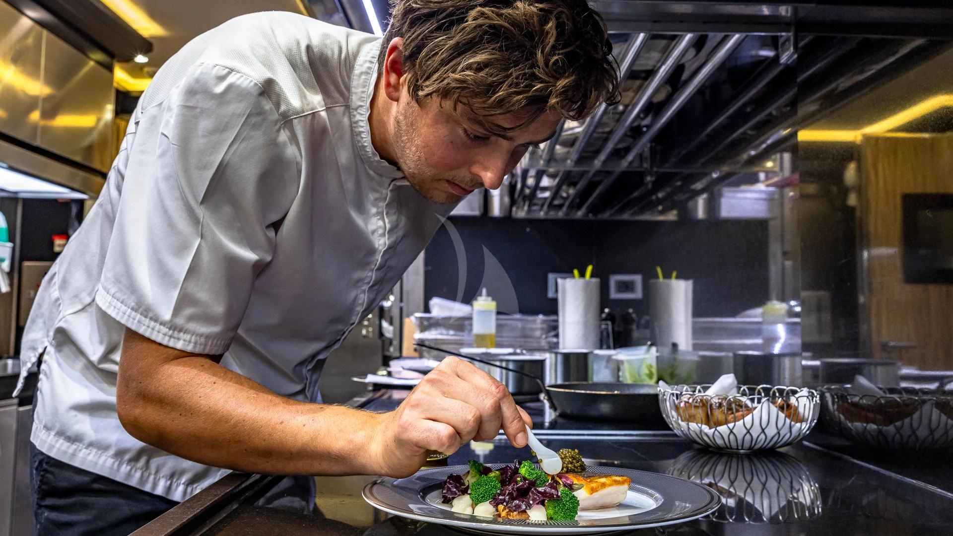 a man preparing food in a kitchen aboard OKTO Yacht for Charter