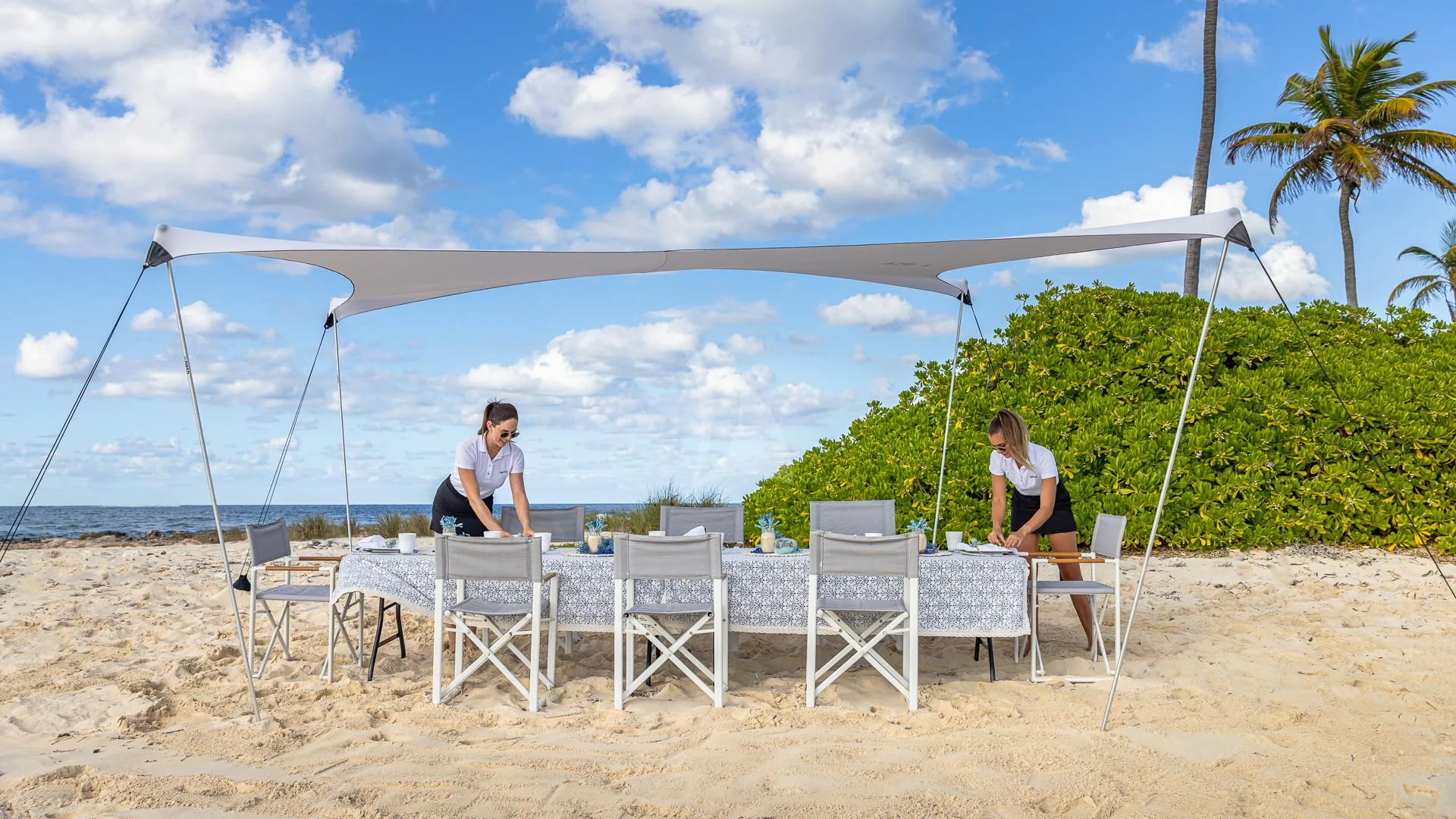 a couple of people sitting on a beach under a tent aboard OKTO Yacht for Charter