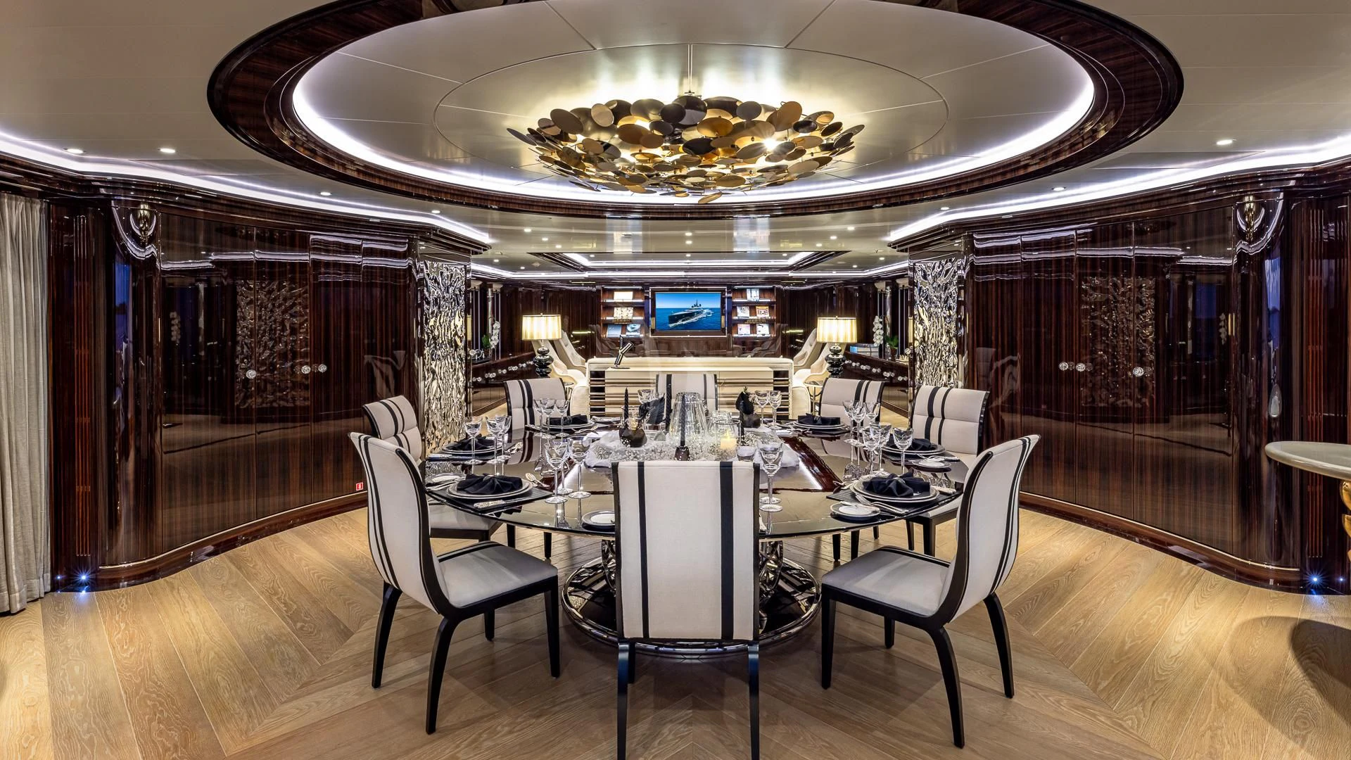 a room with a table chairs and a large chandelier aboard OKTO Yacht for Charter