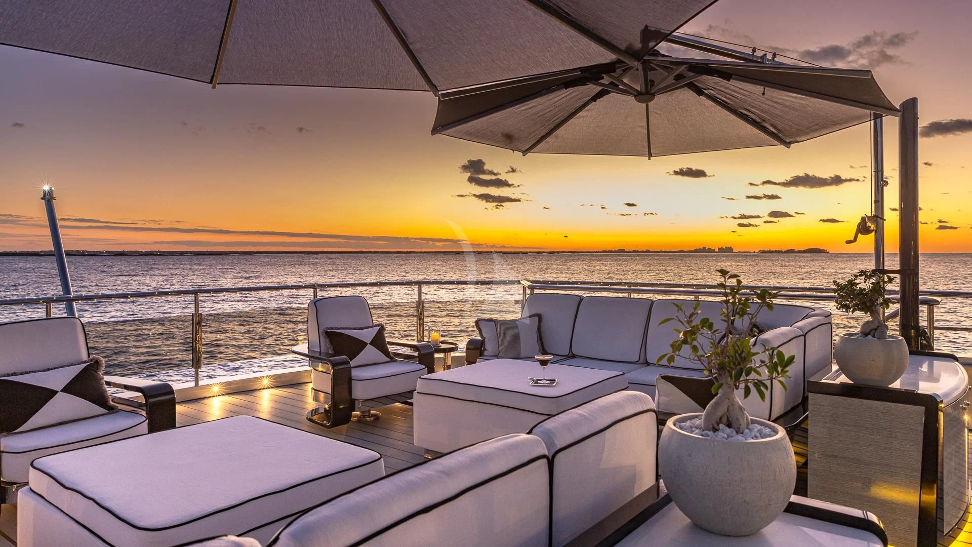 a large lounge area with a large body of water and a large boat in the background aboard OKTO Yacht for Charter