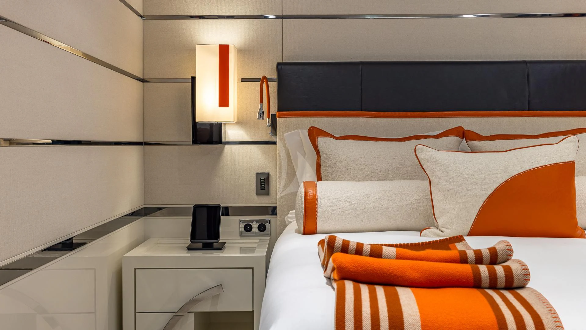 a bed with orange and white pillows aboard OKTO Yacht for Charter
