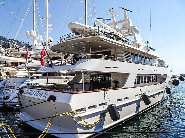 a large white boat with a flag on it aboard AMORAZUR II Yacht for Sale