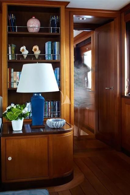 a bookshelf with a lamp and a vase with flowers on it aboard ANCALLIA Yacht for Sale