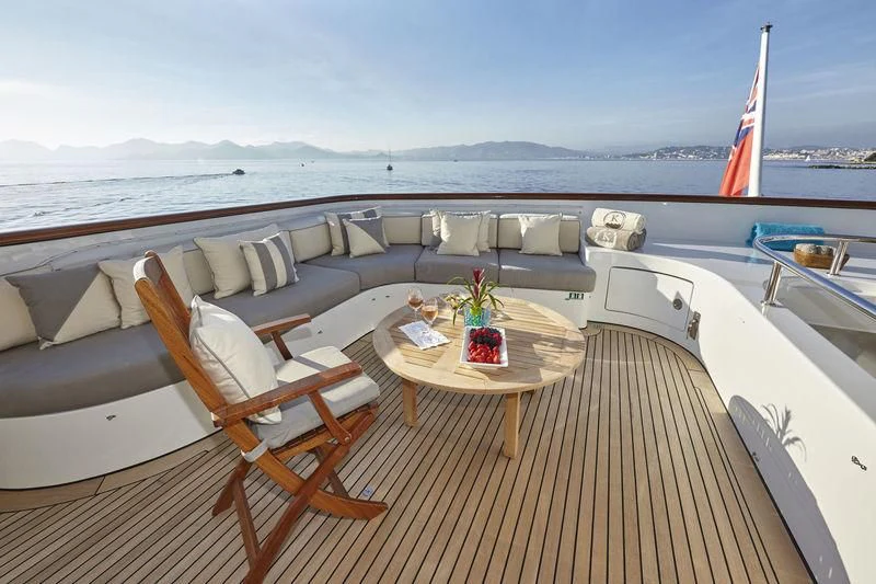 a table and chairs on a deck overlooking a beach aboard AZUL V Yacht for Charter