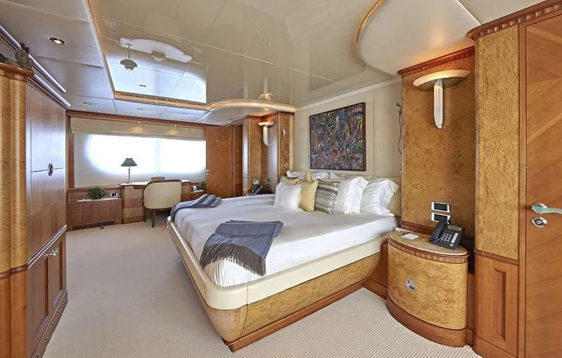 a bedroom with a bed and a wood cabinet aboard AZUL V Yacht for Charter