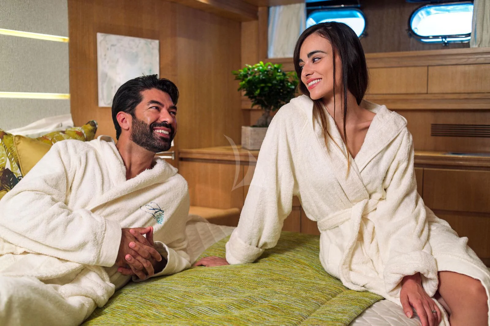 a man and a woman sitting on a bed aboard AMAYA Yacht for Sale