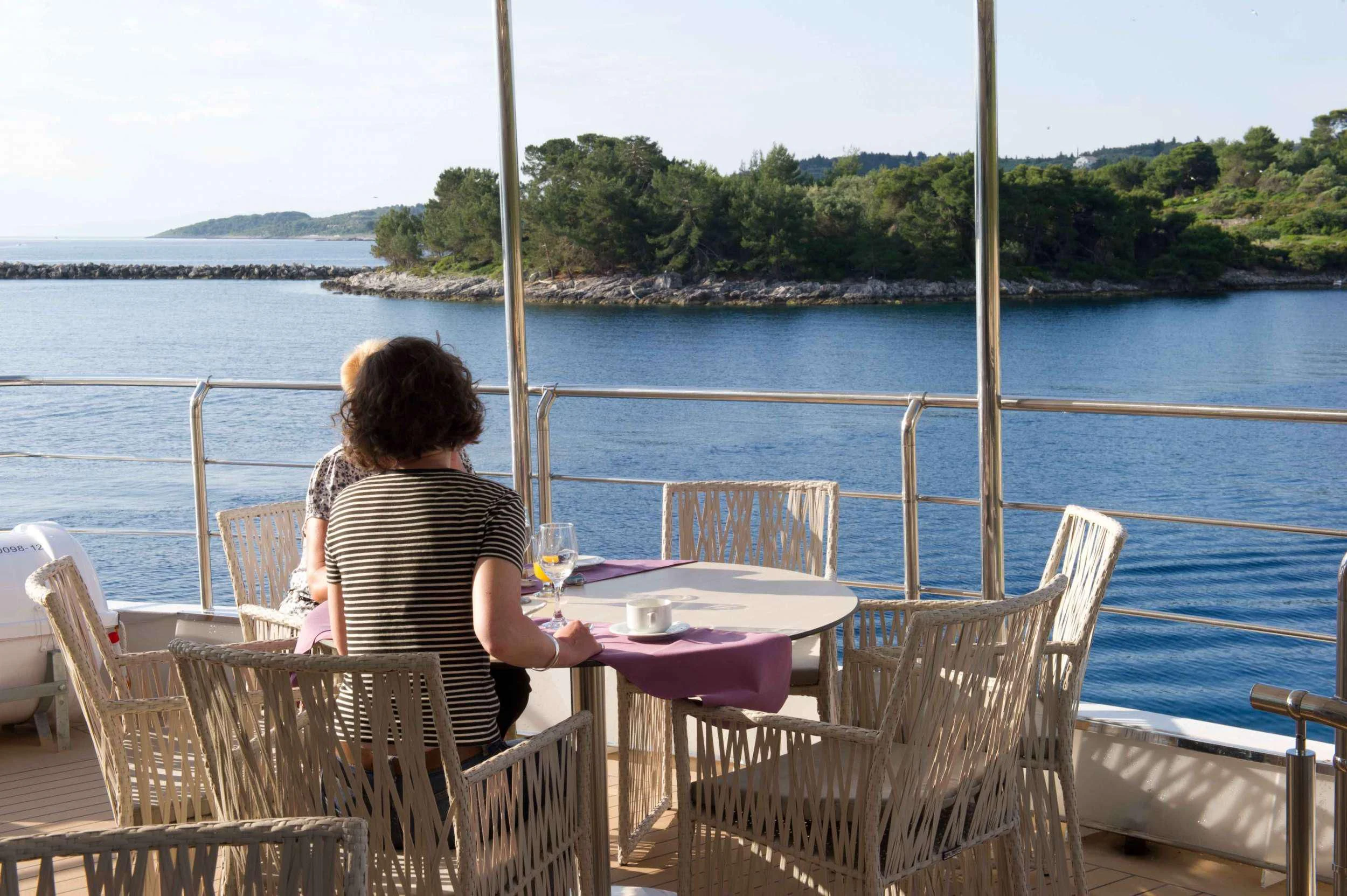 a person sitting at a table looking out at the water aboard VARIETY VOYAGER Yacht for Sale
