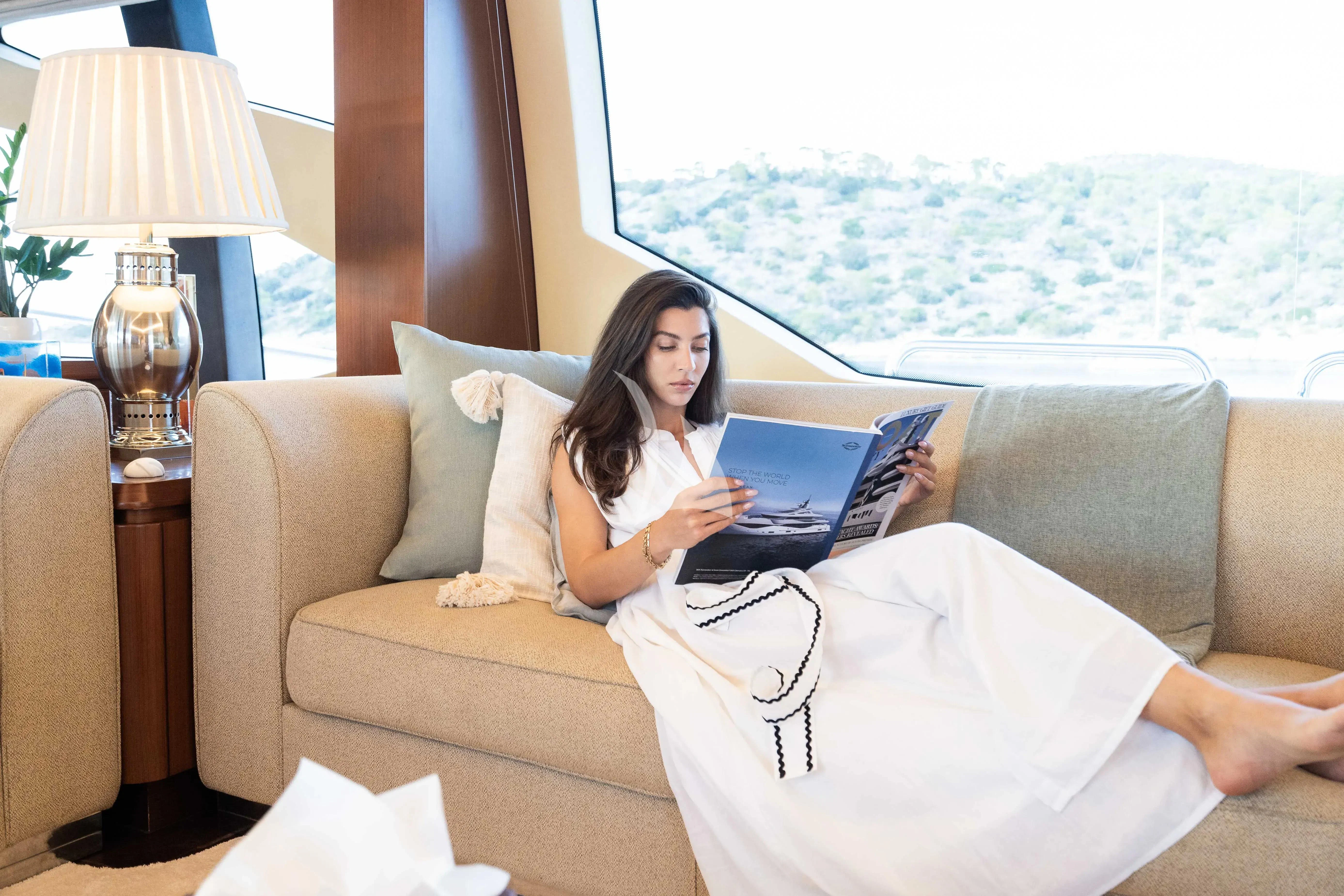 a woman sitting on a couch with a laptop aboard KOUKLES Yacht for Sale