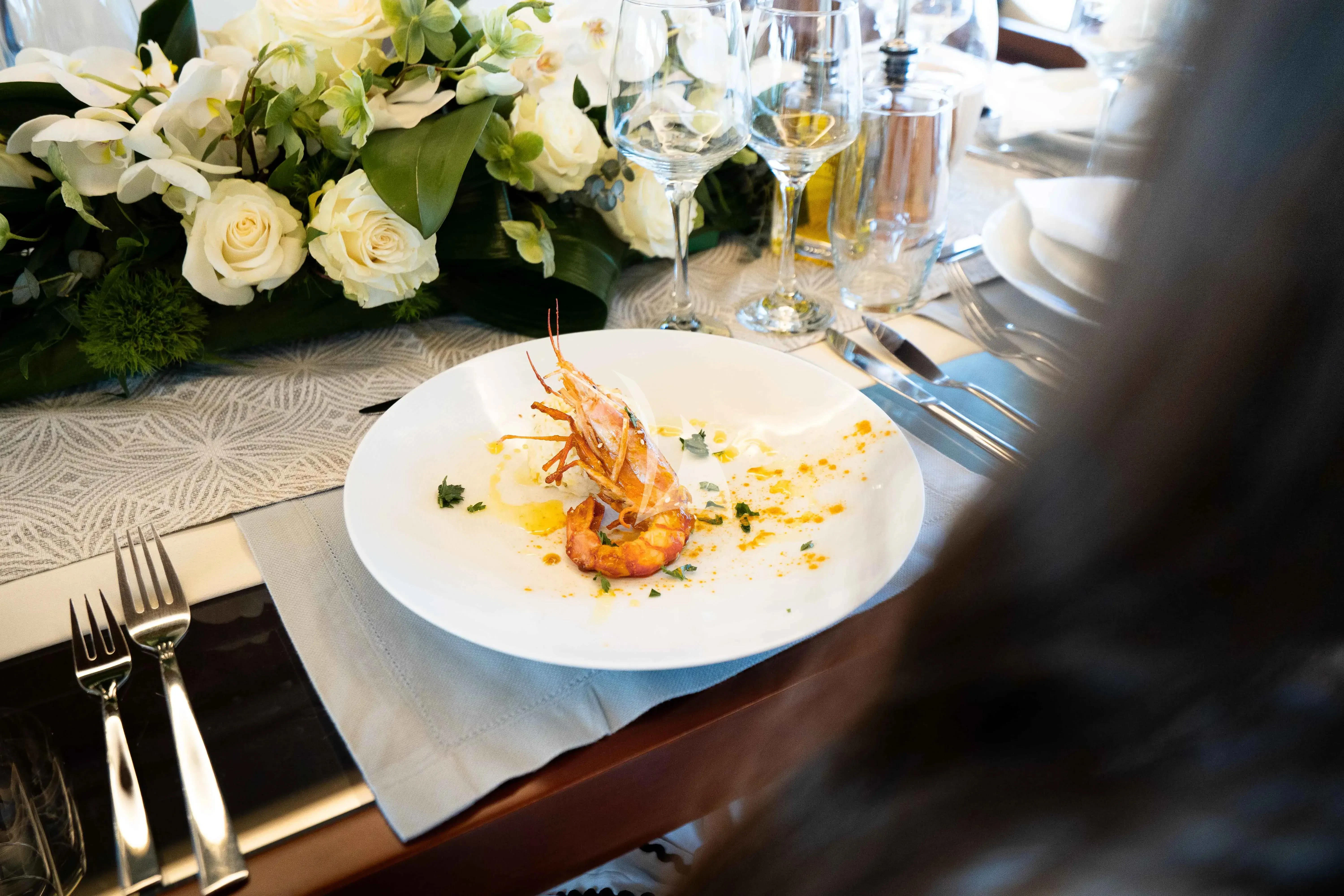 a plate of food and glasses of wine on a table aboard KOUKLES Yacht for Sale