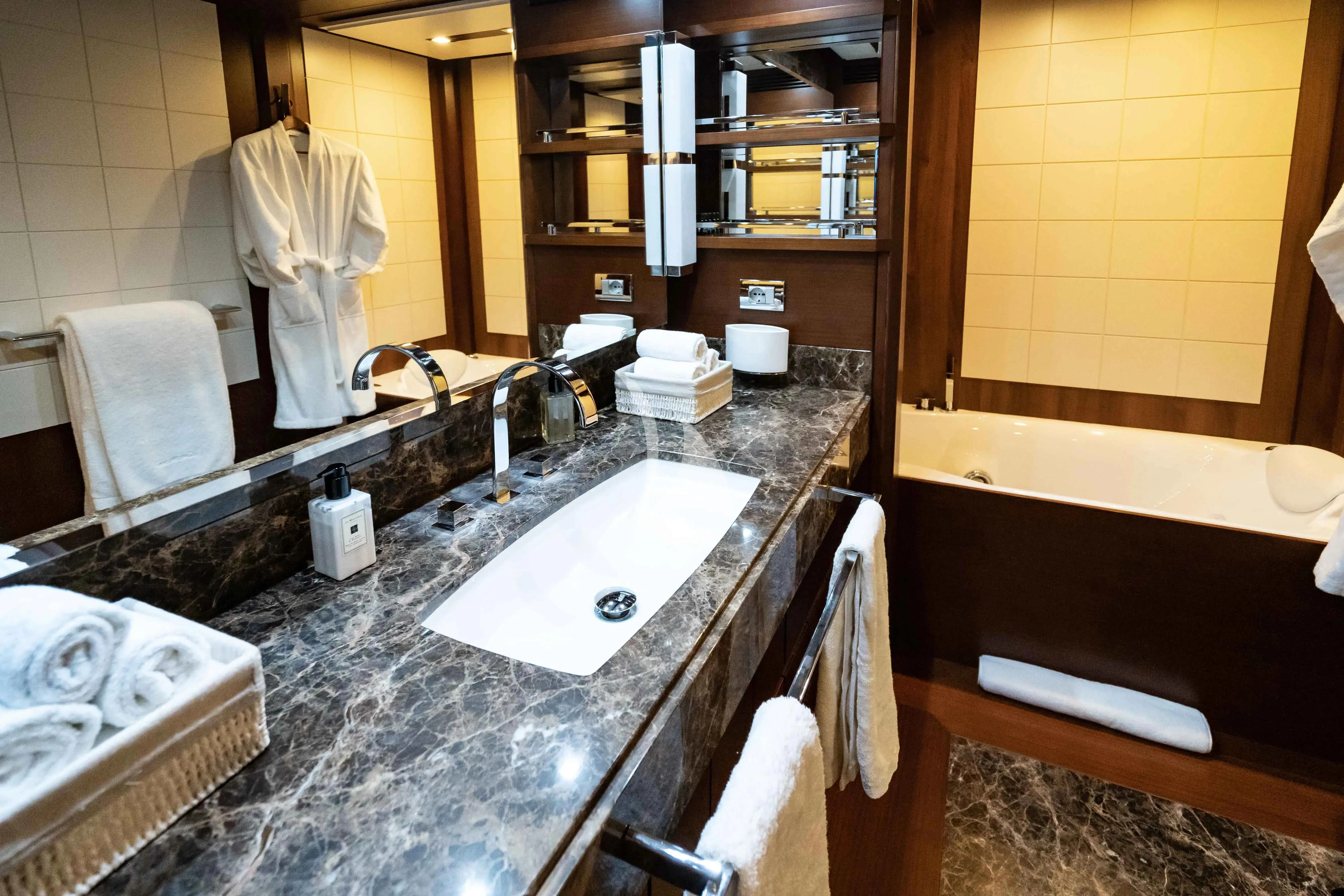 a bathroom with a countertop sink and bathtub aboard KOUKLES Yacht for Sale