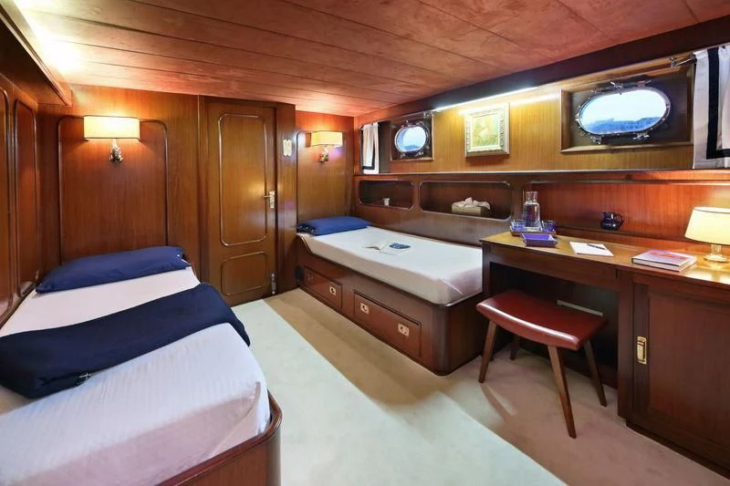 a room with a bed and desk aboard RA Yacht for Sale