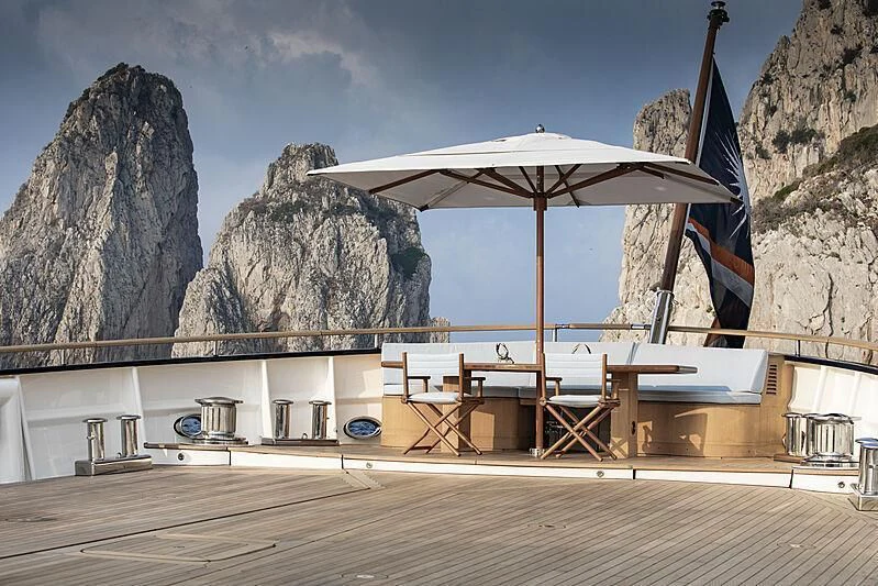 a deck with chairs and an umbrella aboard BLUE II Yacht for Charter