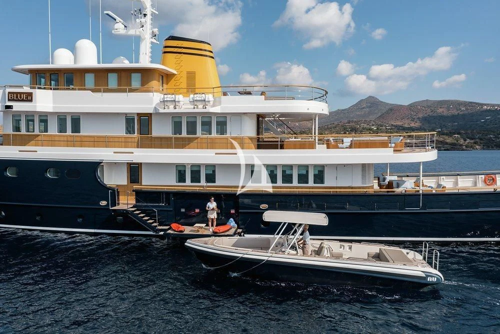 a large white boat with a yellow stripe on the front aboard BLUE II Yacht for Charter