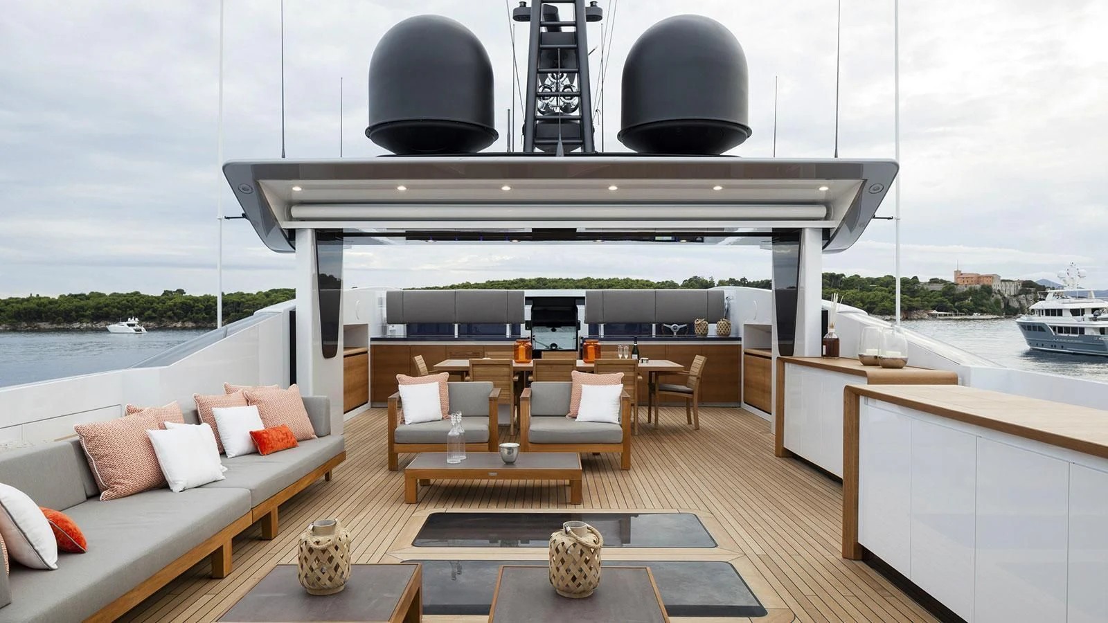 a room with a couch and a table with chairs and a large boat in the background aboard PACHAMAMA Yacht for Sale