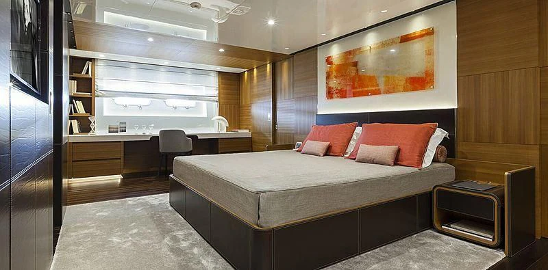 a room with a bed and desk aboard PACHAMAMA Yacht for Sale