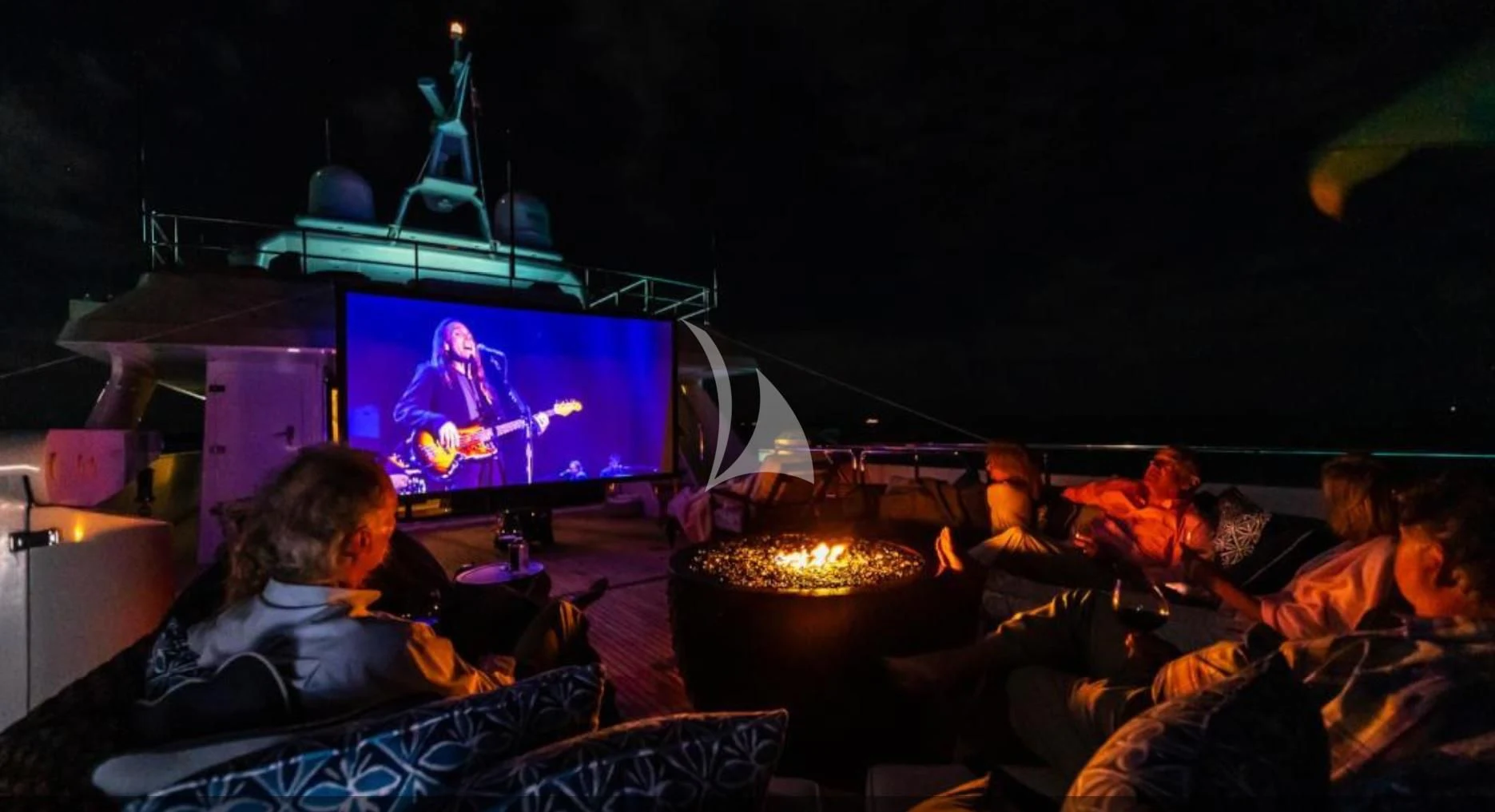 a group of people sitting around a fire in a dark room aboard SEA AXIS Yacht for Charter
