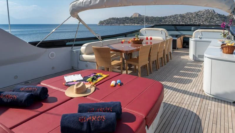 a table on a deck with a view of the ocean and a city aboard GLAROS Yacht for Sale