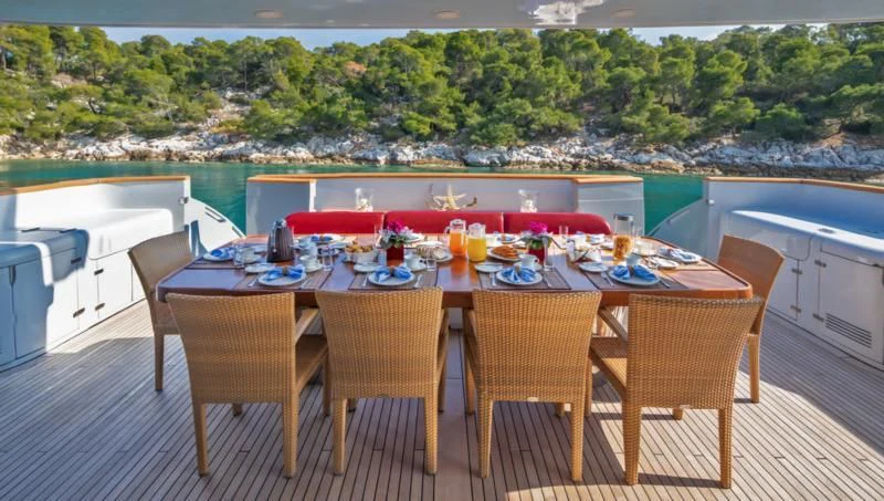 a table set with chairs and a view of a city aboard GLAROS Yacht for Sale