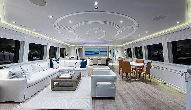 a large living room with a large white sofa and a round table aboard LIBERTAS Yacht for Sale