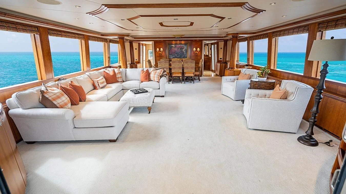 a living room with a large white couch and a large window aboard KEMOSABE Yacht for Charter