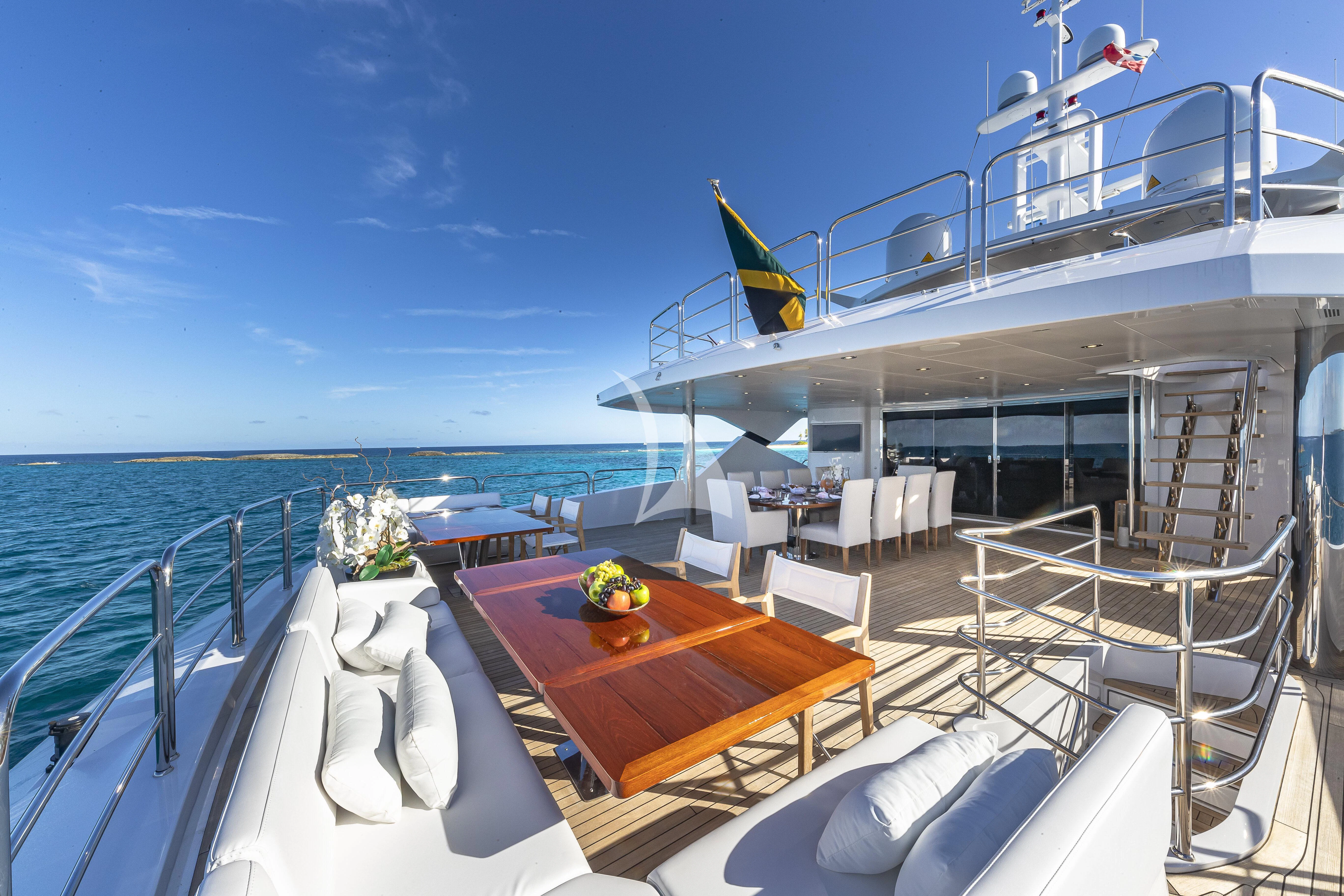 a deck with a table and chairs on it and a large body of water in the background aboard ALESSANDRA III Yacht for Charter