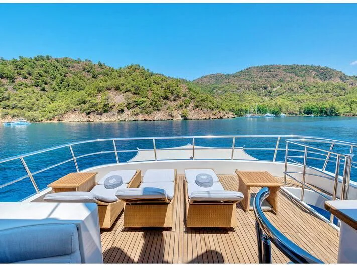 a deck with chairs and tables on it by a body of water aboard BANDIDO I Yacht for Sale