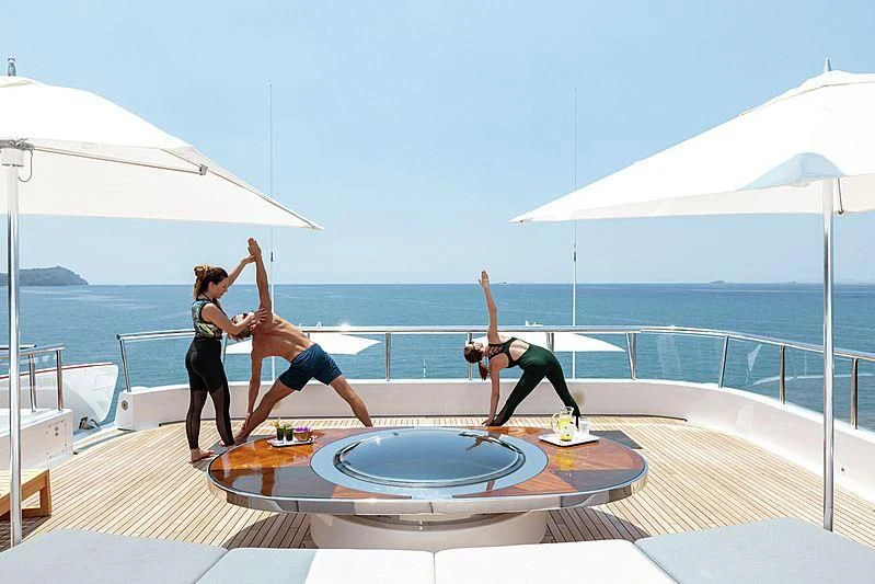 a couple of women doing yoga on a deck by the water aboard FELIX Yacht for Sale