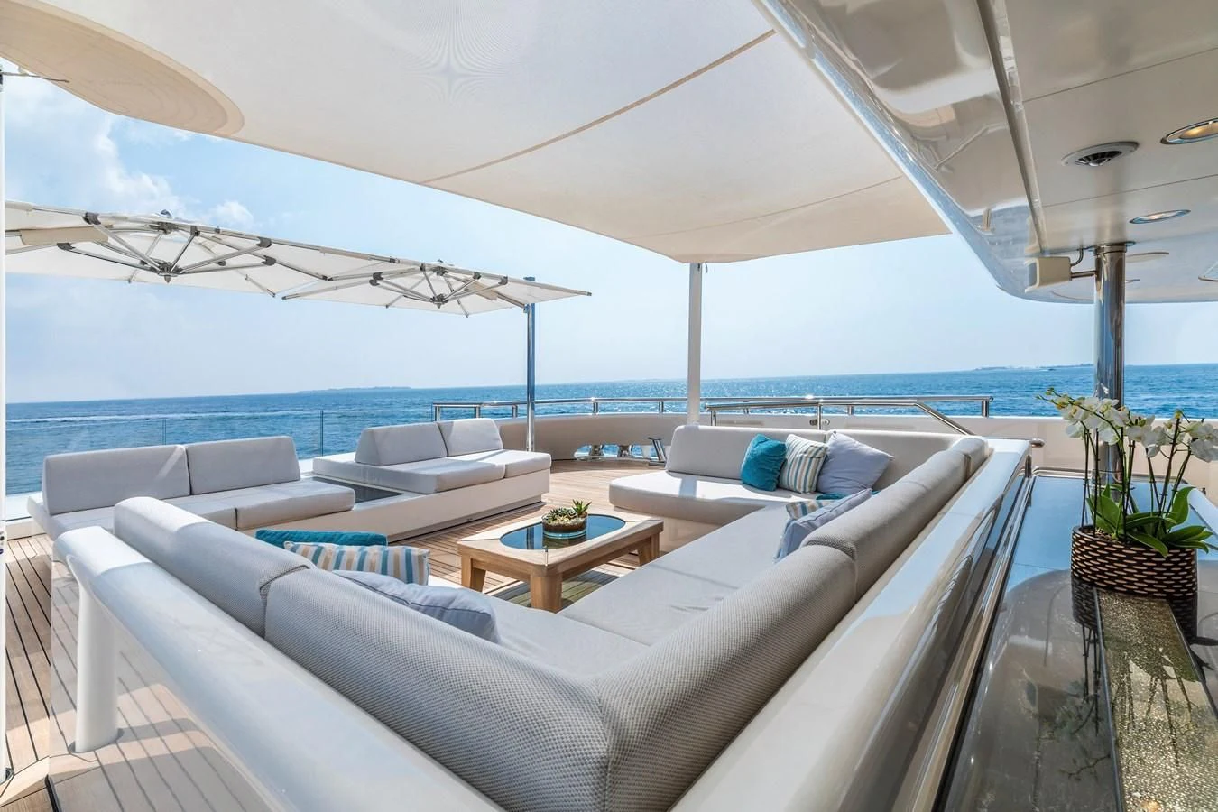 a large white lounge chair next to a large white umbrella on a patio aboard FELIX Yacht for Sale