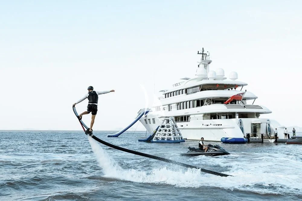 a man on a boat with a paddle and a person on the water aboard FELIX Yacht for Sale