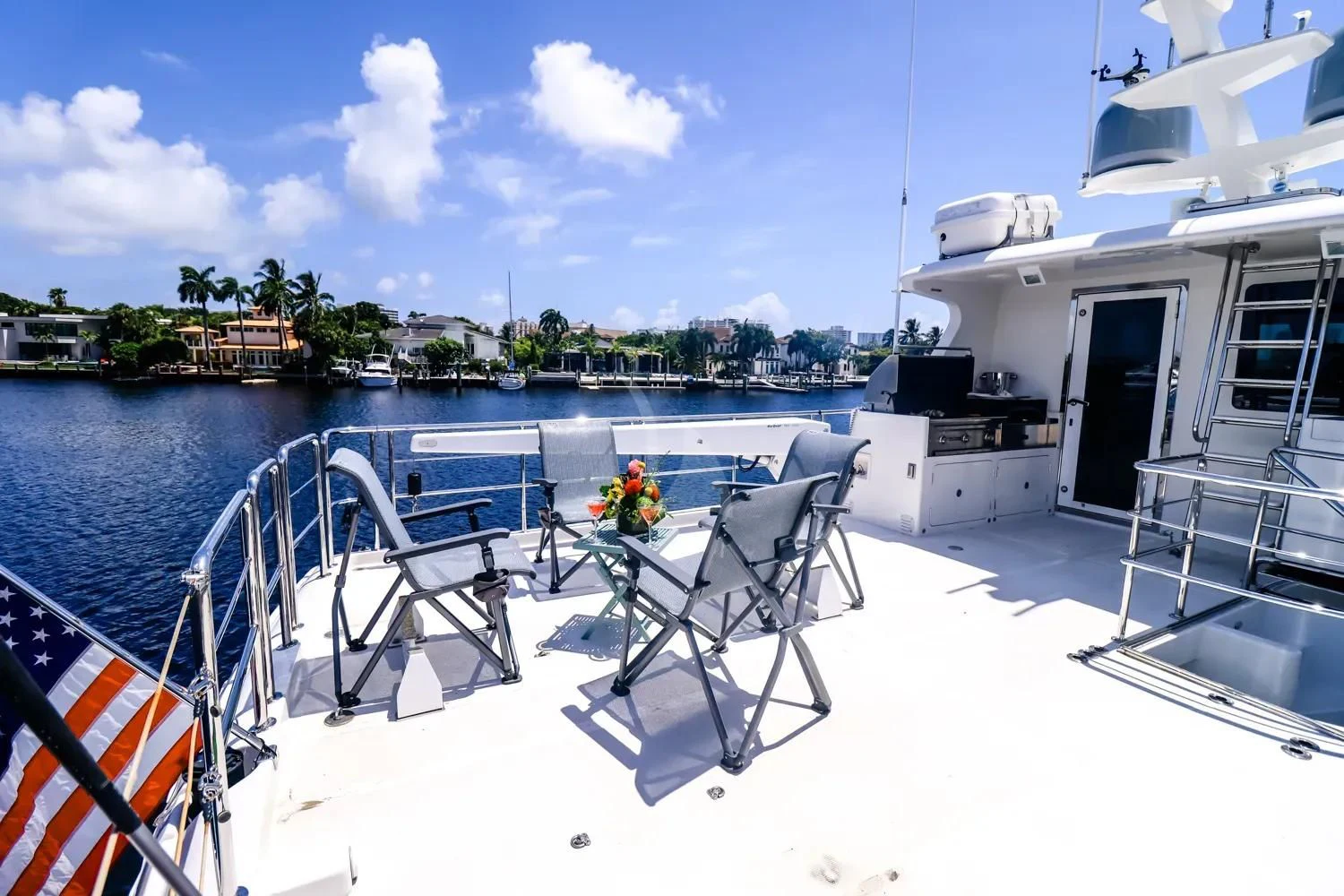 a deck with chairs and a table on it by a body of water aboard ANDIAMO Yacht for Charter