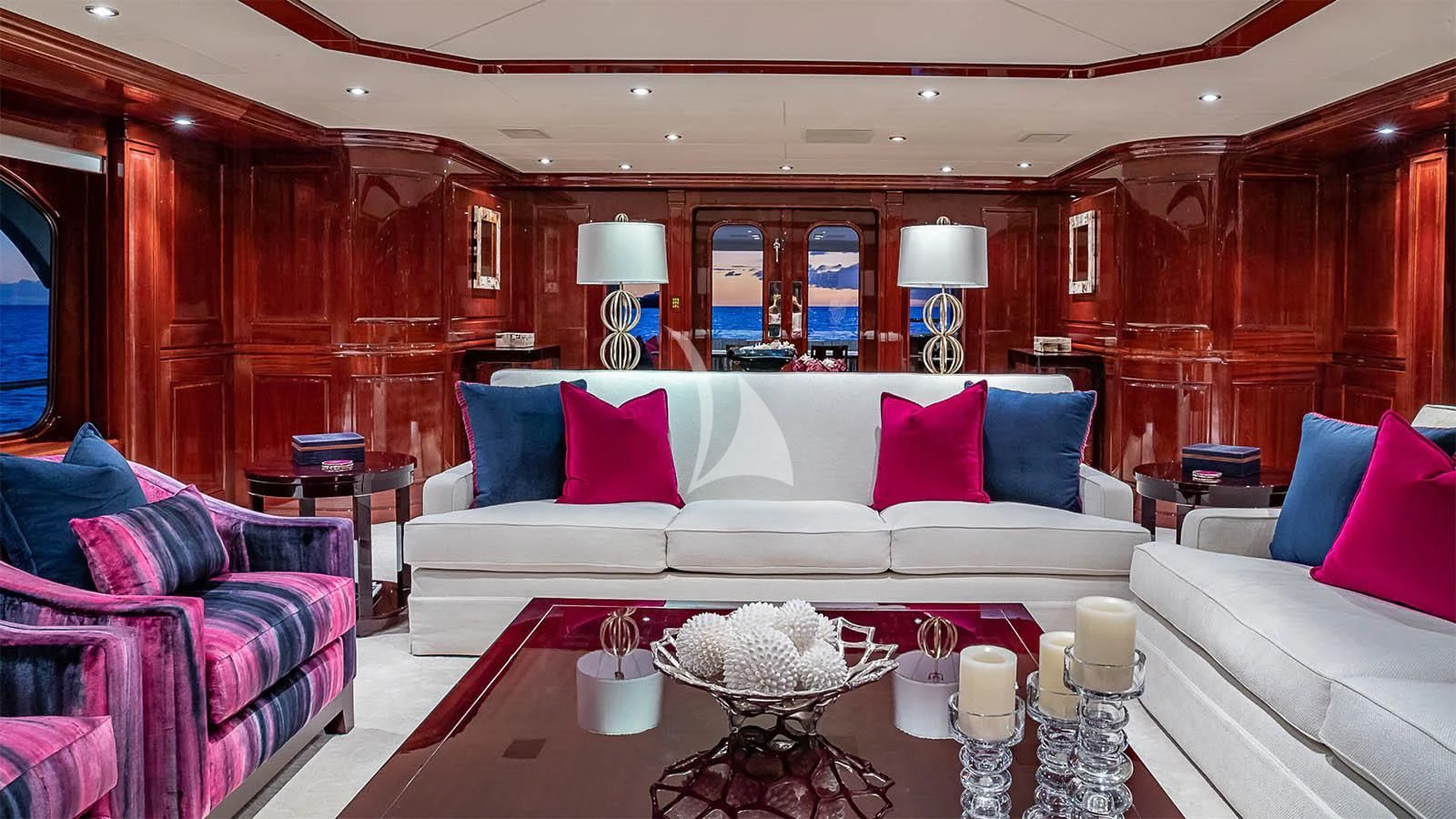a living room with a white couch and a table with candles aboard CARTE BLANCHE Yacht for Charter