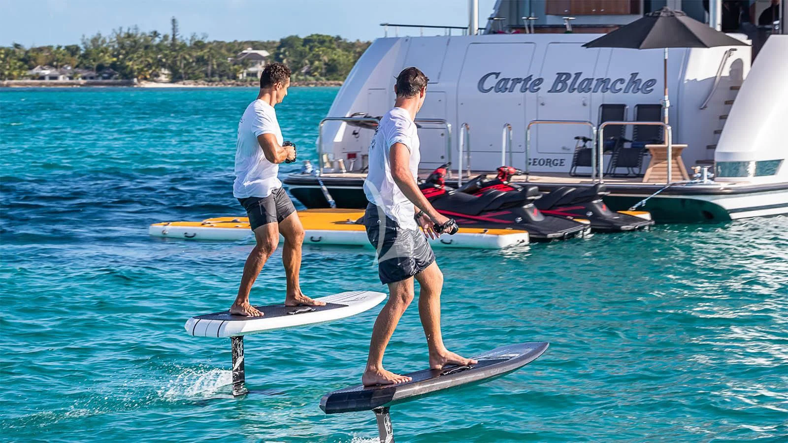 a couple of men stand on surfboards in the water aboard CARTE BLANCHE Yacht for Charter