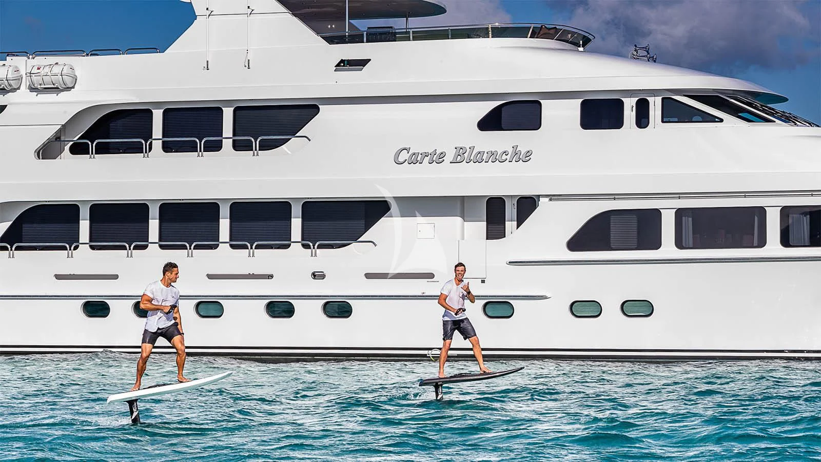 a person on a surfboard in front of a white boat aboard CARTE BLANCHE Yacht for Charter