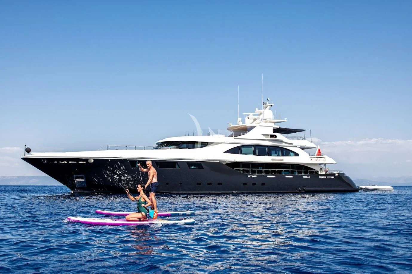 a person paddle boarding in front of a white boat aboard ZIA Yacht for Sale