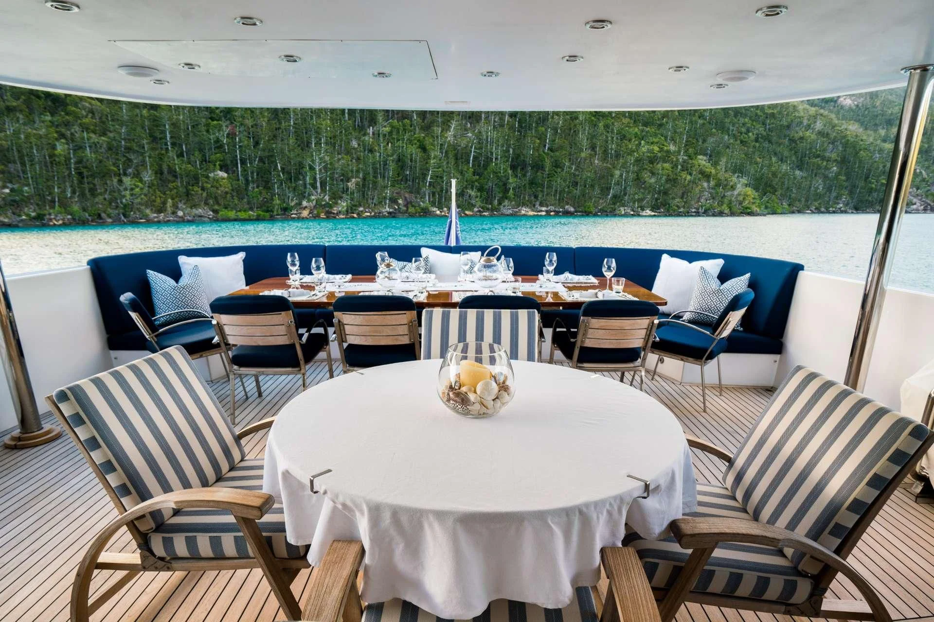 a table set for a meal on a deck overlooking a lake aboard DE LISLE III Yacht for Sale