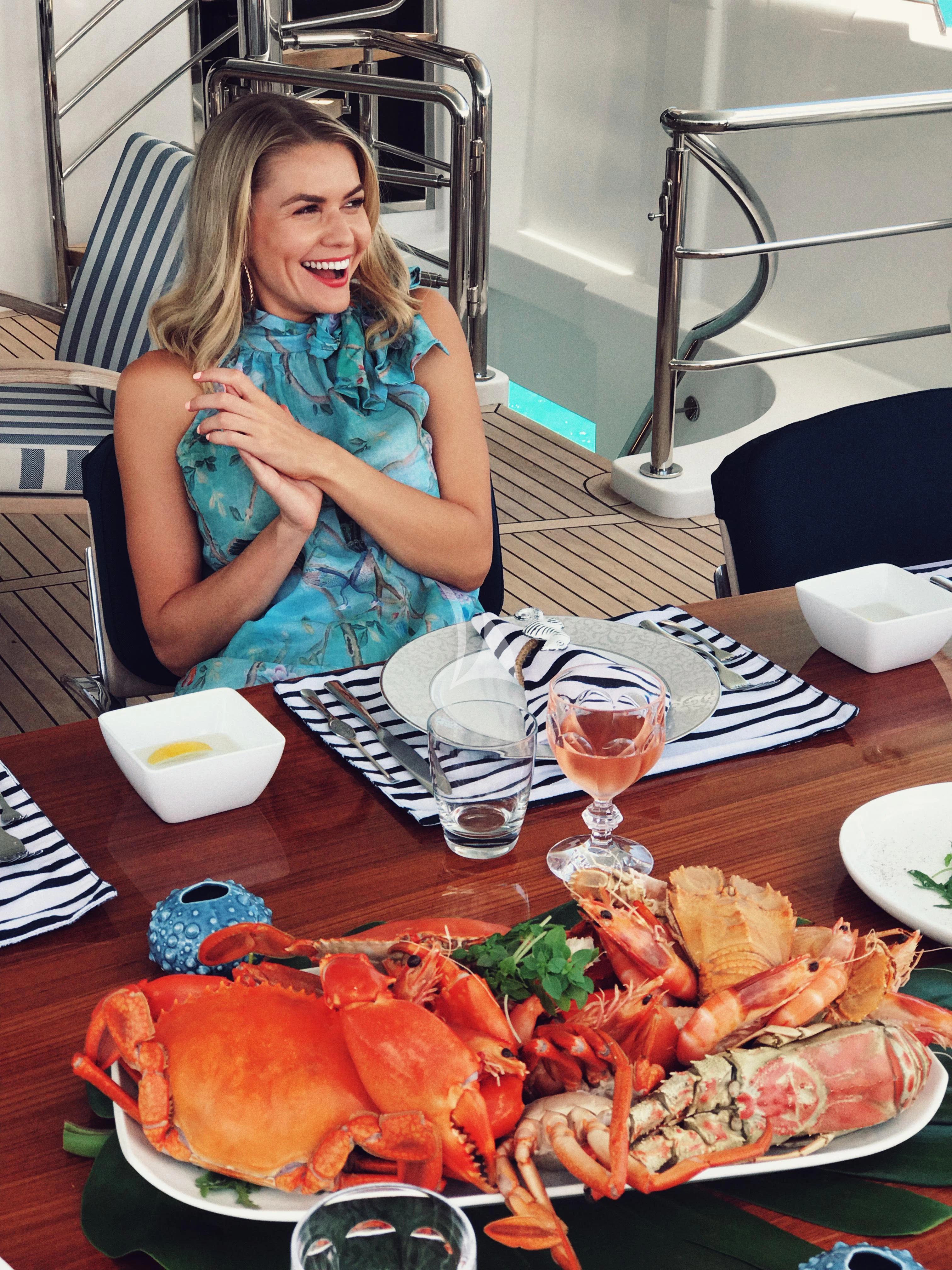 Danielle Byrnes sitting at a table with food and drinks aboard DE LISLE III Yacht for Sale