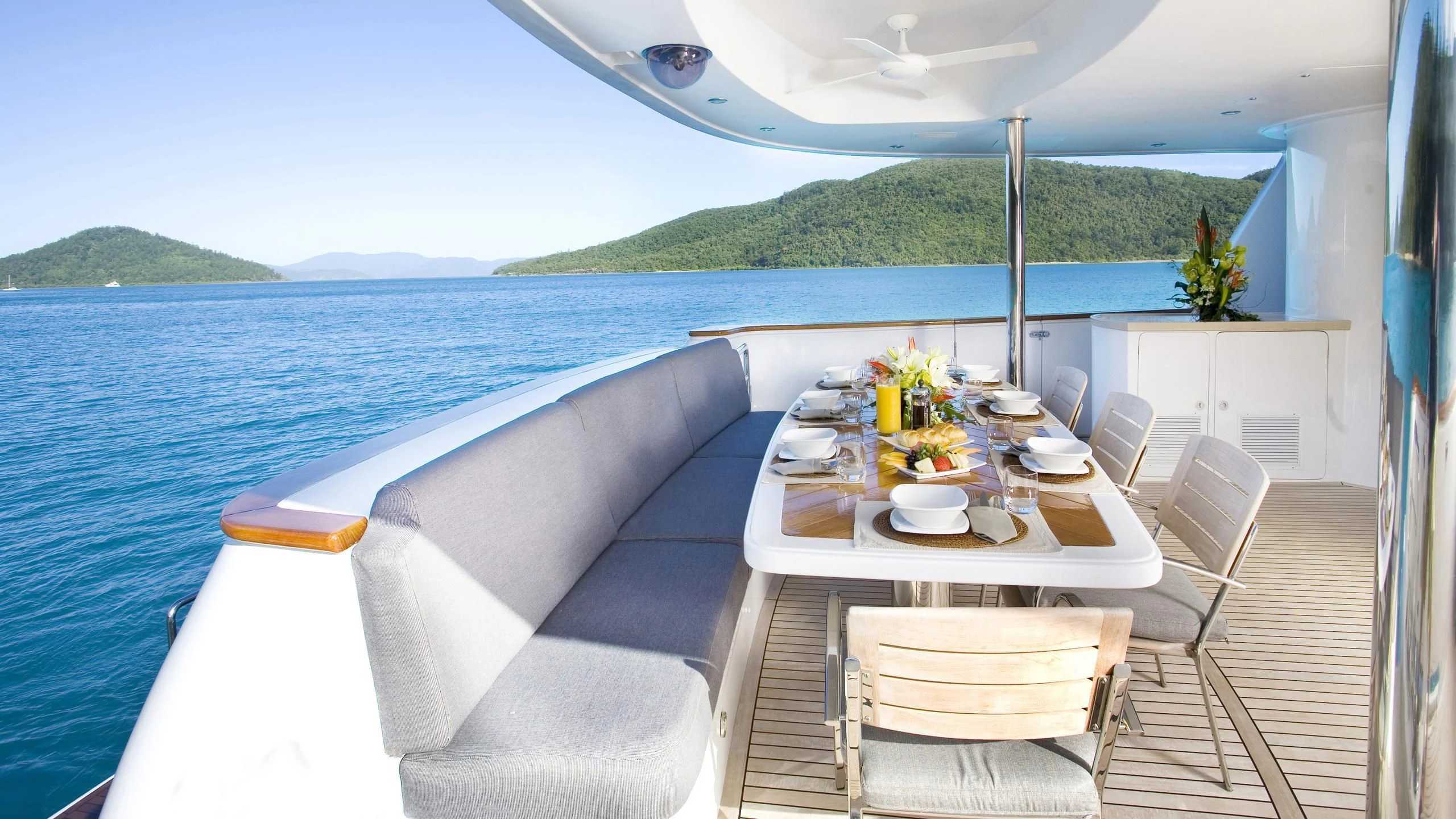 a table on a deck with chairs and a view of the ocean aboard DE LISLE III Yacht for Sale