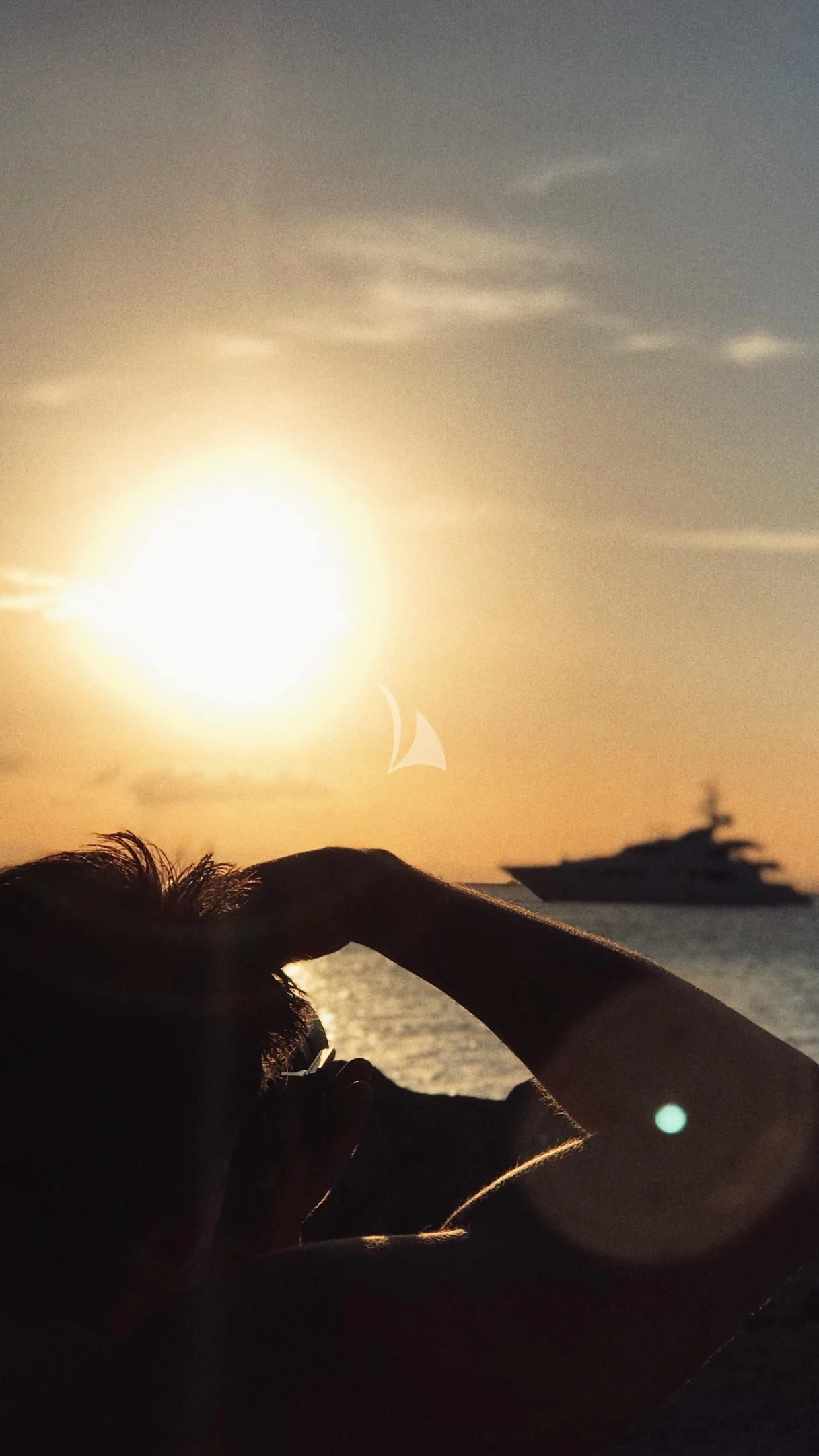 a person's hand holding a piece of wood in front of the sun aboard DE LISLE III Yacht for Sale