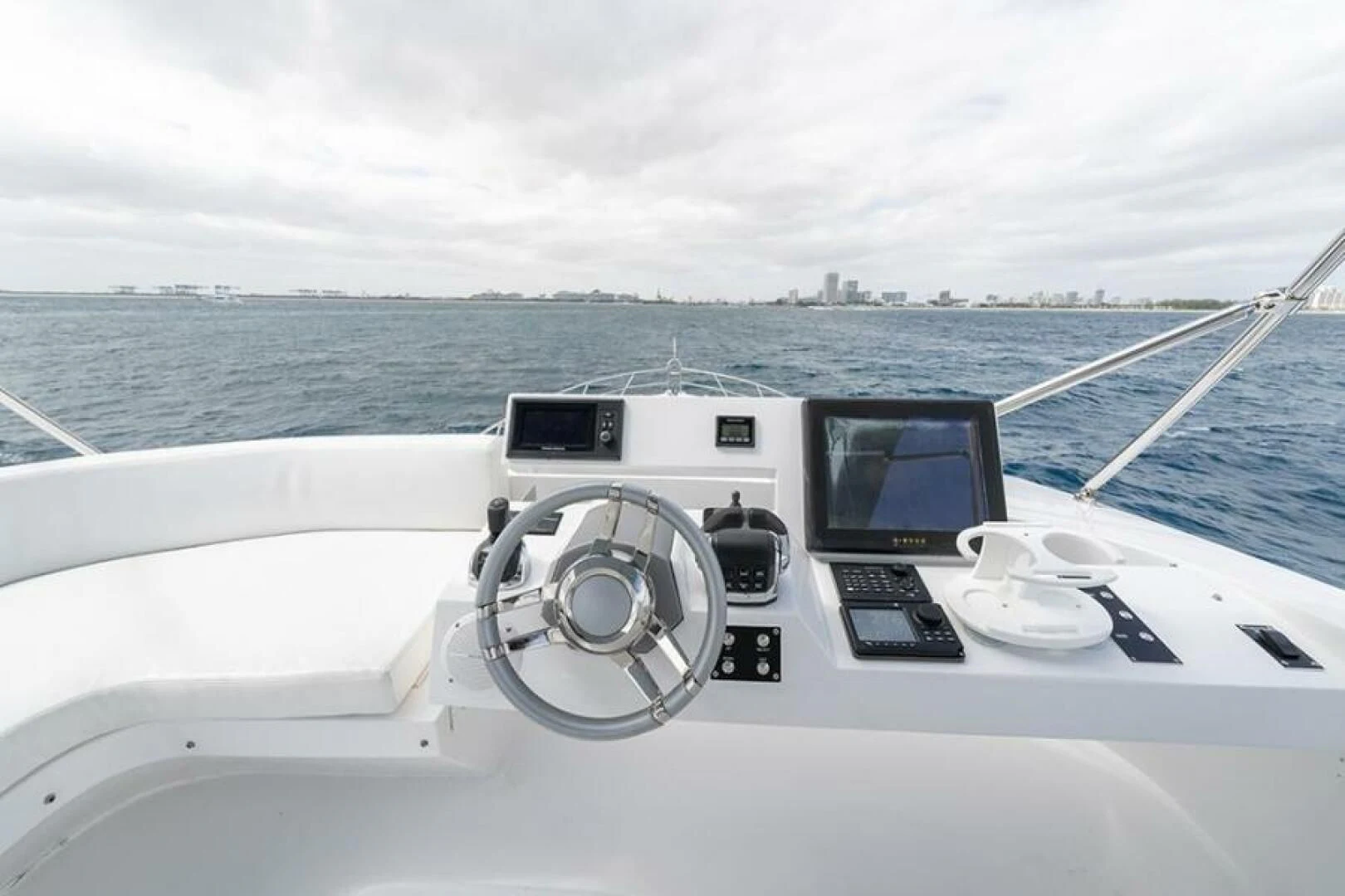a boat with a steering wheel and a city in the background aboard LATITUDE Yacht for Sale