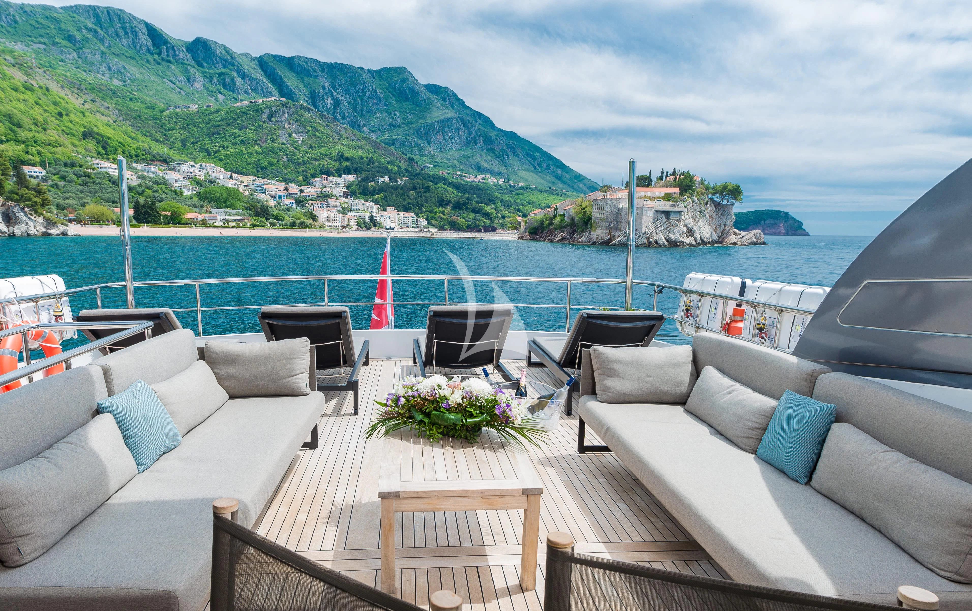 a deck with chairs and a body of water in the background aboard PERTULA Yacht for Sale