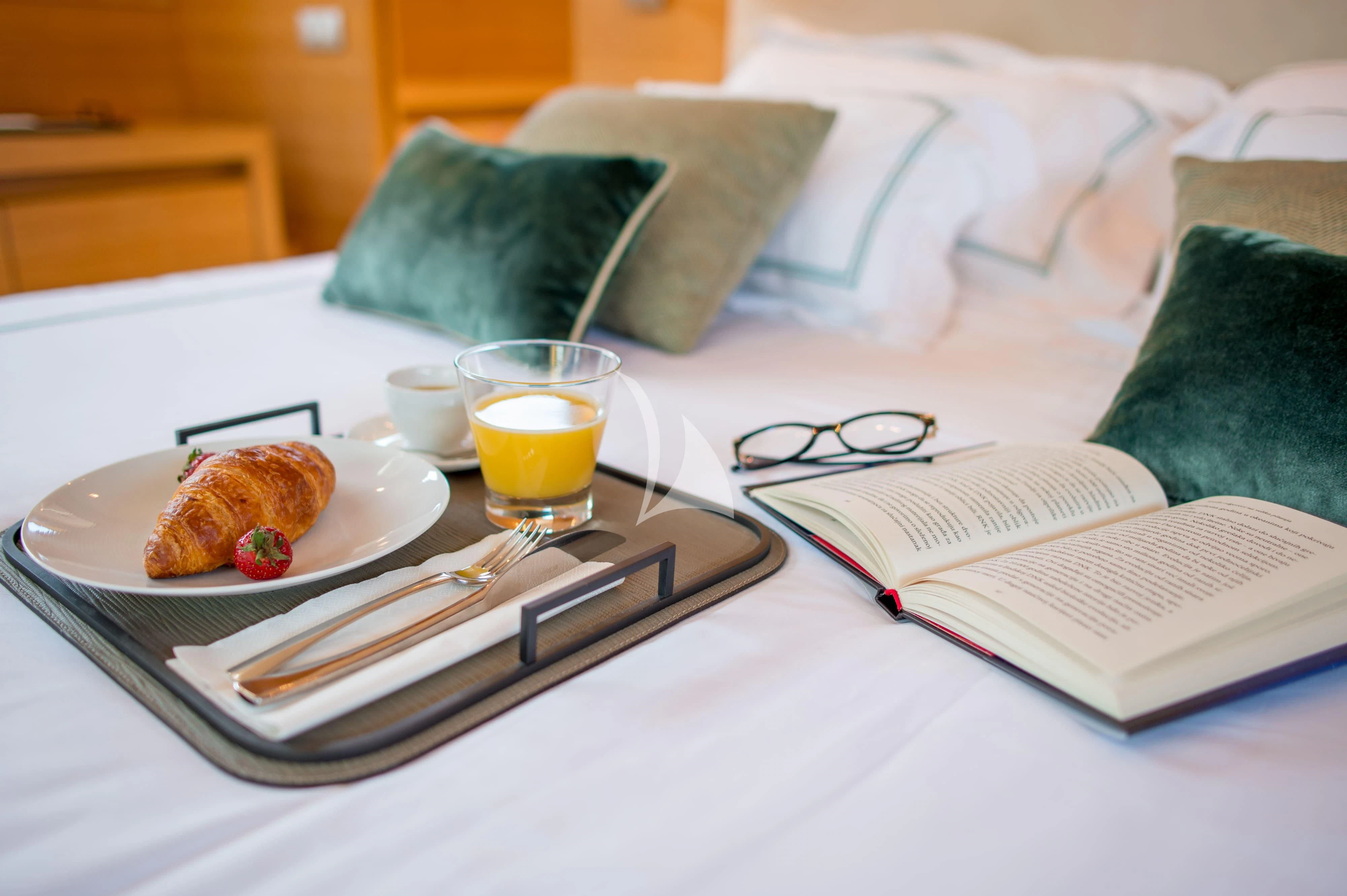 a tray of food and a drink on a bed aboard PERTULA Yacht for Sale