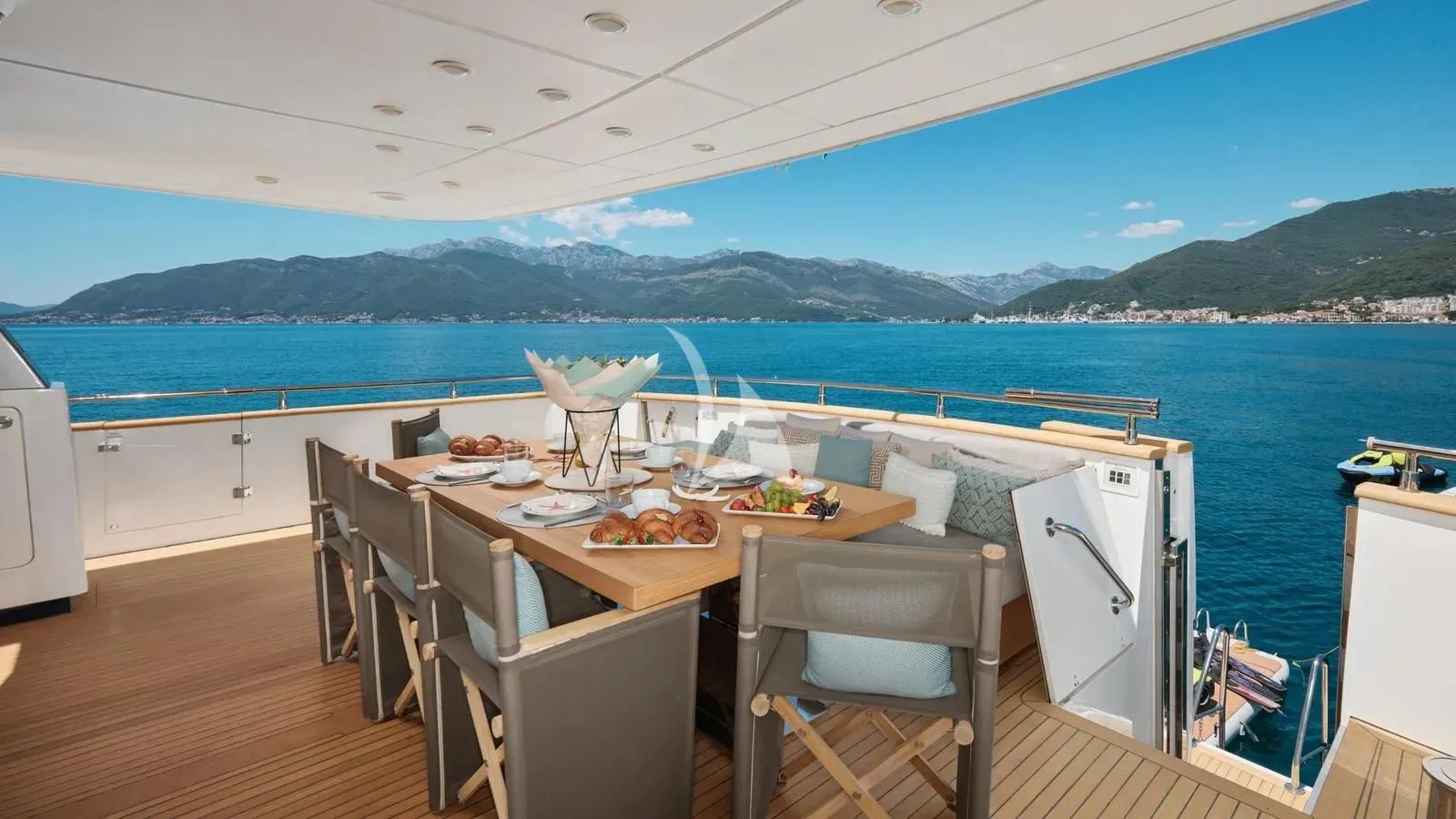 a table on a deck overlooking a body of water aboard PERTULA Yacht for Sale